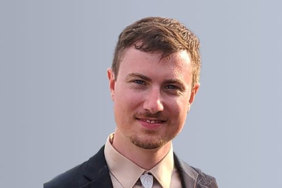Smiling person in a suit with a light gray background